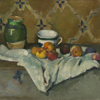 A green jar, patterned cup, and apples sit on a folded white cloth before patterned wallpaper.